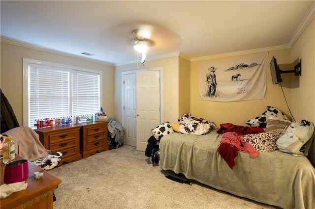 bedroom with ceiling fan, light colored carpet, ornamental molding, and a closet