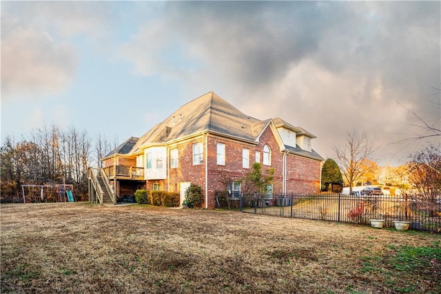 rear view of house featuring brick siding, fence, a wooden deck, and stairway