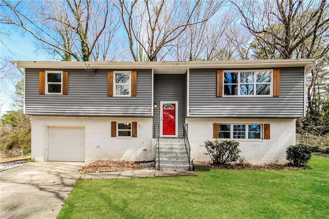 raised ranch featuring driveway, a front lawn, entry steps, a garage, and brick siding