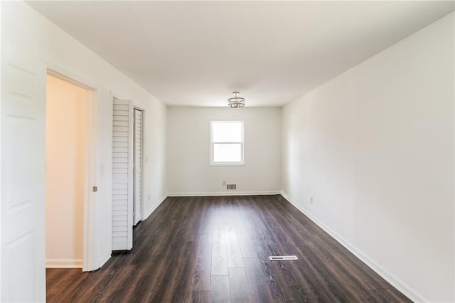 unfurnished room with dark wood finished floors, visible vents, and baseboards
