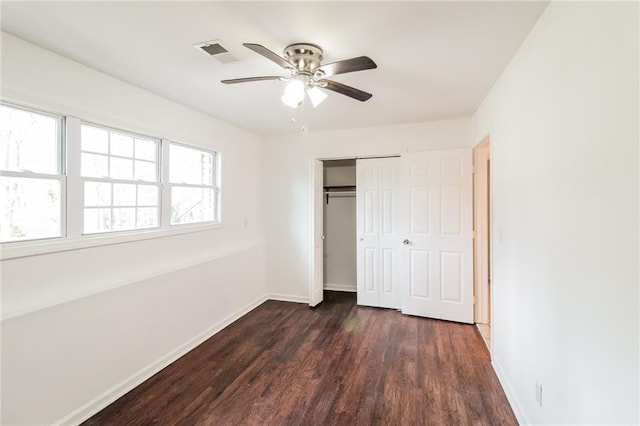 unfurnished bedroom with dark wood finished floors, baseboards, visible vents, and a closet