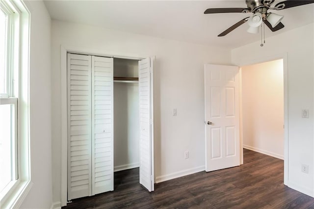 unfurnished bedroom with dark wood-type flooring, multiple windows, and a closet