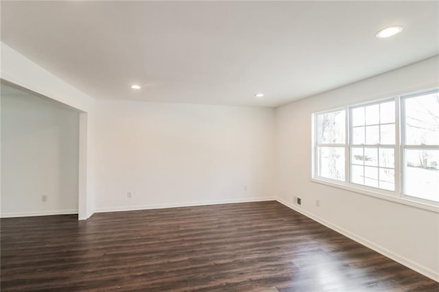 spare room featuring recessed lighting, baseboards, and dark wood-type flooring