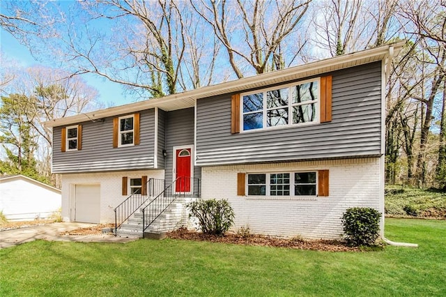 split foyer home featuring a garage, driveway, brick siding, and a front yard