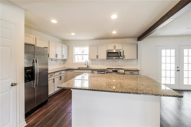 kitchen featuring a sink, a center island, stone counters, stainless steel appliances, and dark wood-style flooring