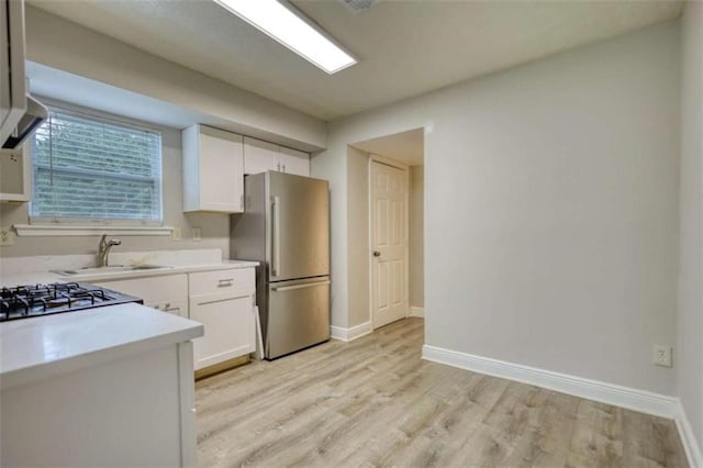 924 Park Gate Pl, Stone Mountain, GA 30083 - kitchen with freestanding refrigerator, white cabinetry, a sink, and light wood-style flooring