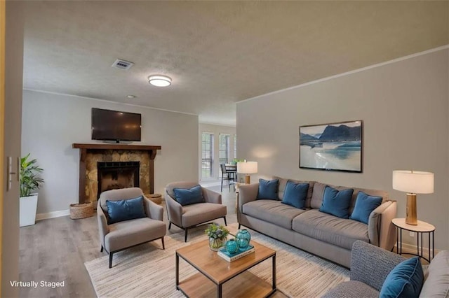 924 Park Gate Pl, Stone Mountain, GA 30083 - living room with wood finished floors, a stone fireplace, ornamental molding, baseboards, and a textured ceiling