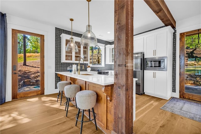 1132 N Edgewater Trl, Toccoa, GA 30577 - kitchen with appliances with stainless steel finishes, a breakfast bar area, light wood finished floors, white cabinetry, and tasteful backsplash