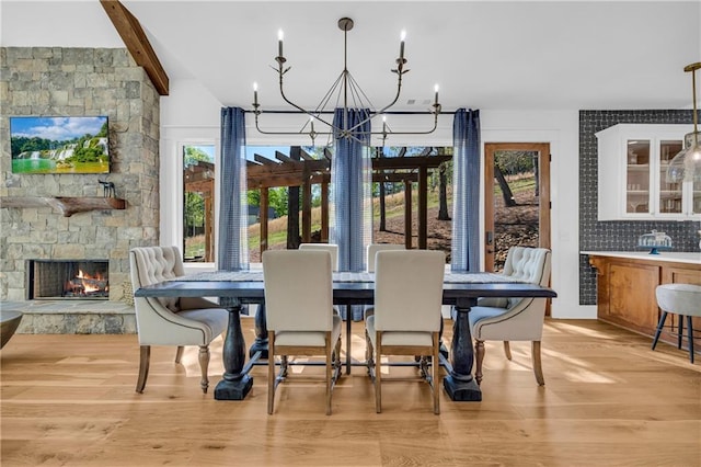 1132 N Edgewater Trl, Toccoa, GA 30577 - dining area featuring light wood-style flooring, a chandelier, a stone fireplace, and beam ceiling