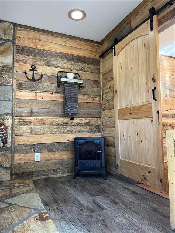 room details with a wood stove, a barn door, wooden walls, and wood finished floors