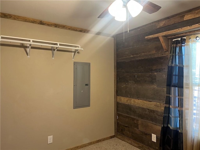 interior space featuring wood walls, electric panel, baseboards, and a ceiling fan