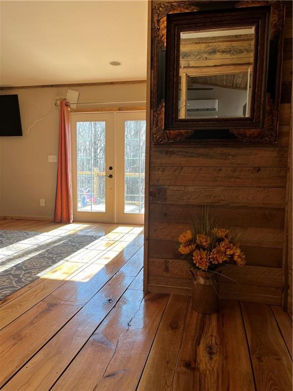 interior space with french doors, wood-type flooring, and a wall unit AC