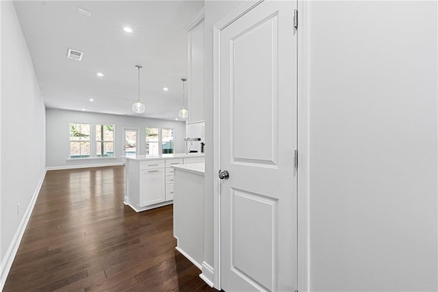 kitchen featuring dark wood-type flooring, white cabinetry, kitchen peninsula, and pendant lighting