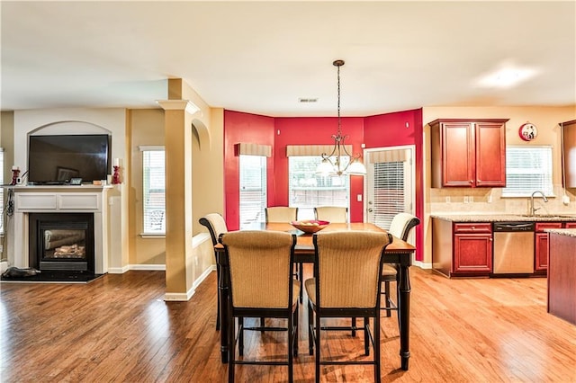 dining space featuring sink, a notable chandelier, and light hardwood / wood-style flooring