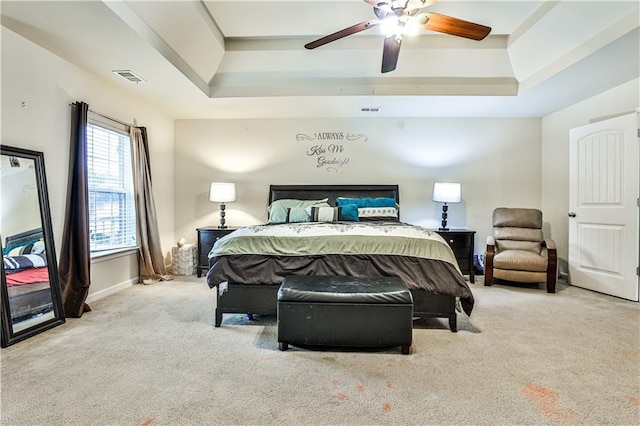 carpeted bedroom featuring a raised ceiling and ceiling fan