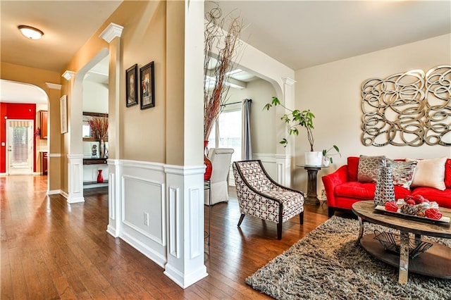 living area with ornate columns and dark wood-type flooring