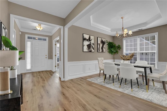 dining room featuring a chandelier, light wood-type flooring, and a tray ceiling