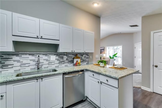 kitchen featuring a peninsula, stainless steel dishwasher, a sink, and white cabinetry