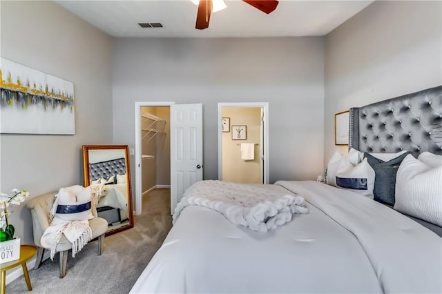 bedroom with carpet floors, a spacious closet, visible vents, and a ceiling fan