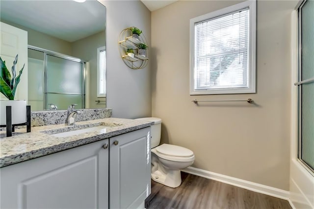 bathroom featuring toilet, a shower with shower door, wood finished floors, vanity, and baseboards