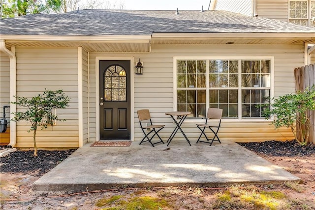 doorway to property with a patio area and roof with shingles