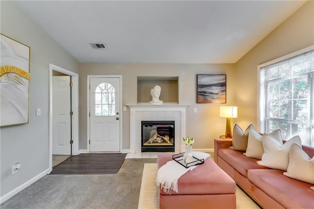 living area with carpet, a tile fireplace, visible vents, and baseboards