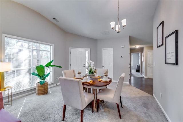 dining room featuring baseboards, carpet flooring, visible vents, and a notable chandelier