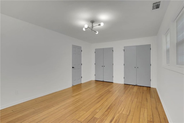 6914 Fairway Trl, Austell, GA 30168 - unfurnished bedroom featuring a chandelier, light wood-style flooring, baseboards, visible vents, and two closets