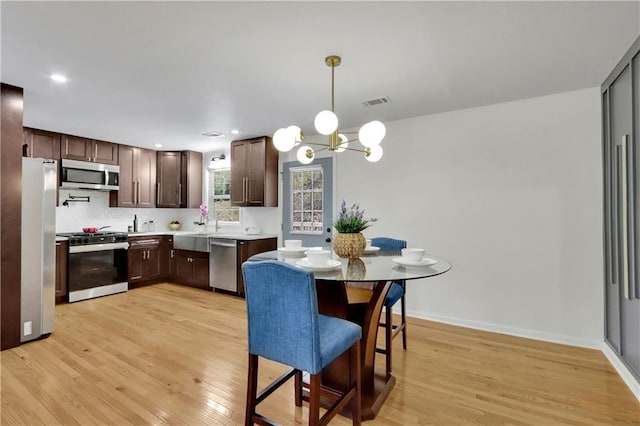6914 Fairway Trl, Austell, GA 30168 - kitchen with light countertops, light wood-style flooring, stainless steel appliances, dark brown cabinets, and an inviting chandelier
