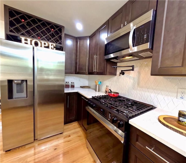 6914 Fairway Trl, Austell, GA 30168 - kitchen with light countertops, light wood-style flooring, dark brown cabinets, appliances with stainless steel finishes, and backsplash
