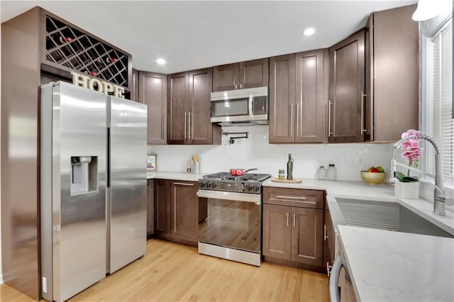 6914 Fairway Trl, Austell, GA 30168 - kitchen with a sink, light stone countertops, appliances with stainless steel finishes, light wood-style floors, and dark brown cabinets