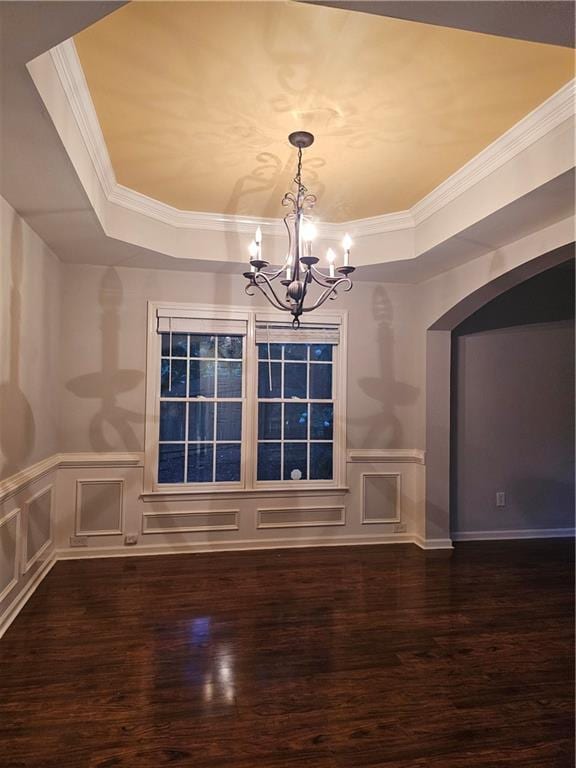 unfurnished dining area featuring a notable chandelier, dark wood-type flooring, and a tray ceiling