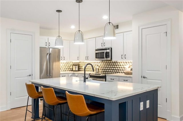 200 River Vista Dr Unit 426, Atlanta, GA 30339 - kitchen featuring tasteful backsplash, an island with sink, stainless steel appliances, white cabinets, and a sink