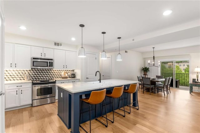 200 River Vista Dr Unit 426, Atlanta, GA 30339 - kitchen featuring appliances with stainless steel finishes, white cabinetry, decorative backsplash, and light wood-style floors