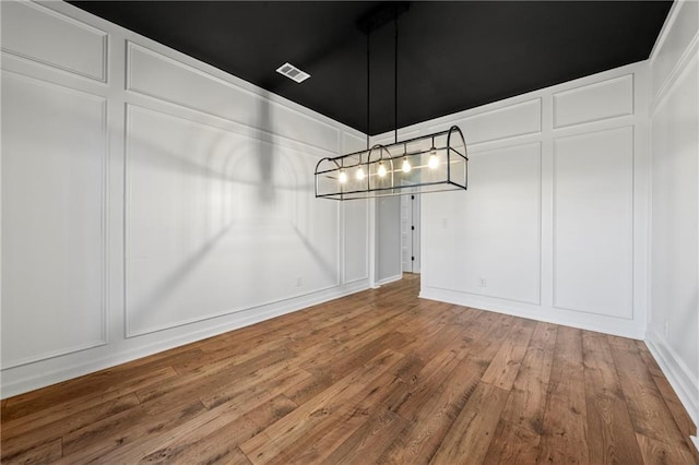 unfurnished dining area with hardwood / wood-style flooring and a chandelier