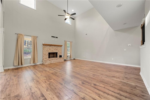 unfurnished living room with a towering ceiling, ceiling fan, and light wood-type flooring