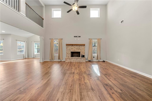 unfurnished living room featuring ceiling fan, a healthy amount of sunlight, a fireplace, and light hardwood / wood-style flooring