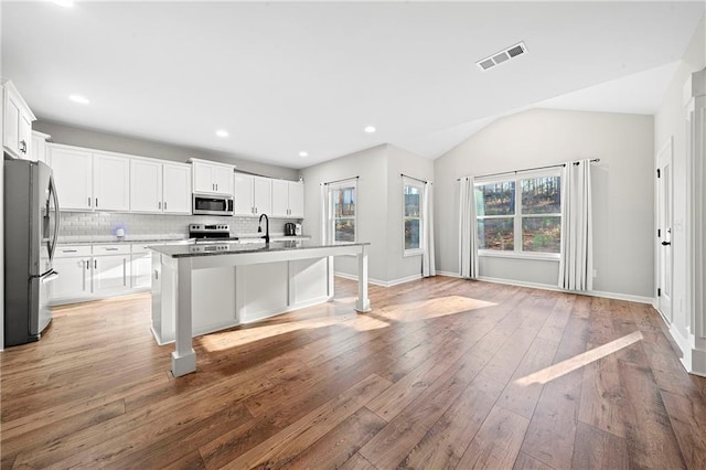 kitchen featuring white cabinetry, stainless steel appliances, a breakfast bar, and a center island with sink