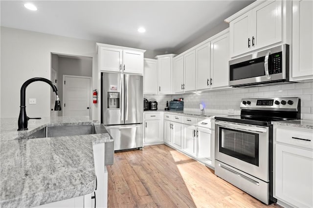 kitchen with white cabinetry, decorative backsplash, and stainless steel appliances