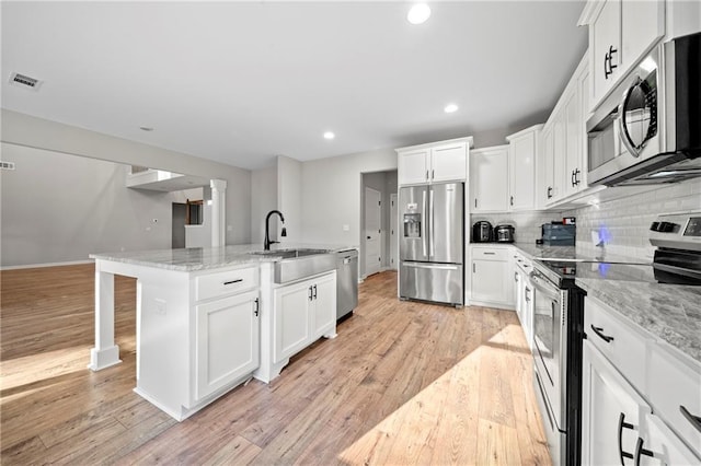 kitchen with stainless steel appliances, sink, an island with sink, and white cabinets