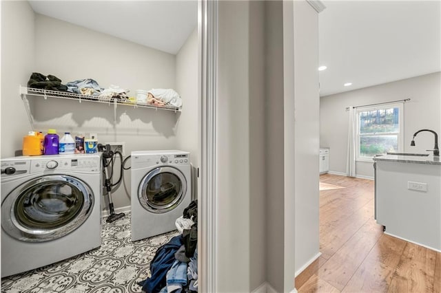 laundry room with sink, washer and clothes dryer, and light hardwood / wood-style floors