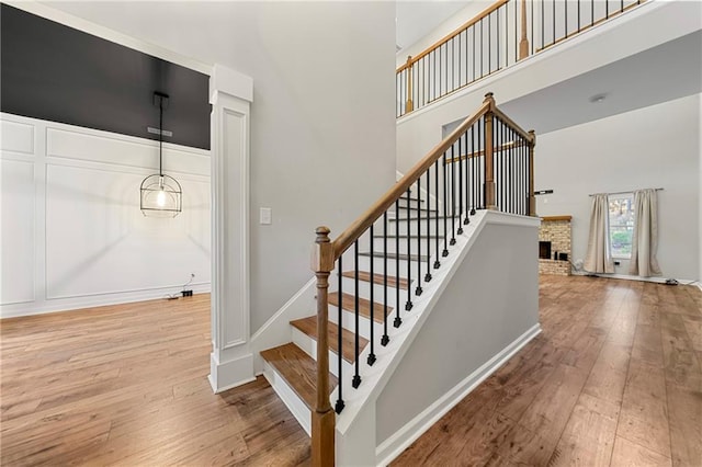 stairway featuring hardwood / wood-style flooring, a fireplace, and a high ceiling