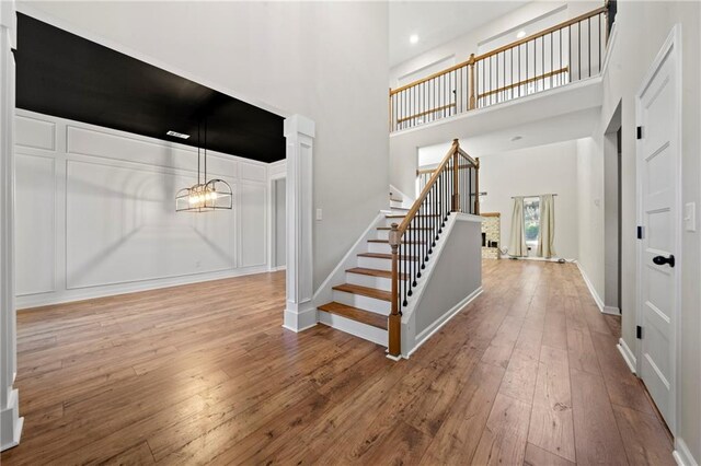 entrance foyer with an inviting chandelier, hardwood / wood-style floors, and a high ceiling