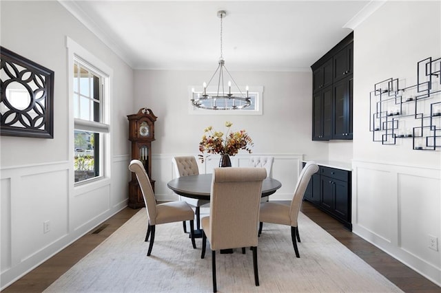168 Brighton Blvd, Woodstock, GA 30188 - dining space with a chandelier, dark wood-type flooring, a decorative wall, crown molding, and a wainscoted wall