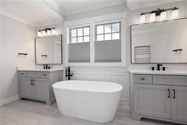 168 Brighton Blvd, Woodstock, GA 30188 - full bathroom featuring a decorative wall, two vanities, a freestanding tub, ornamental molding, and wainscoting