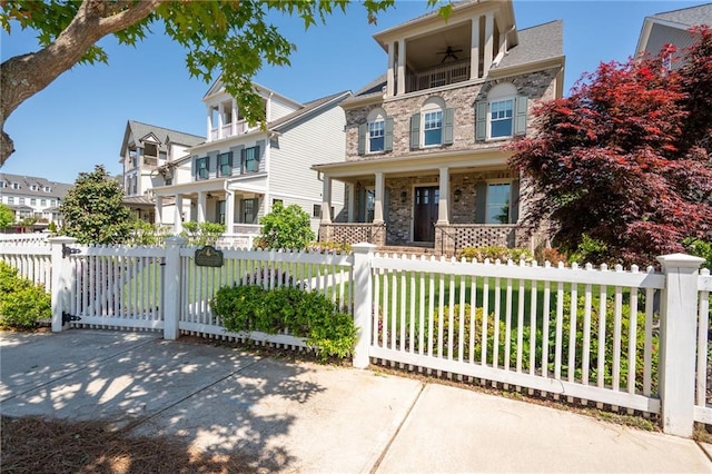 168 Brighton Blvd, Woodstock, GA 30188 - view of front of property with a porch, a balcony, ceiling fan, a fenced front yard, and stone siding