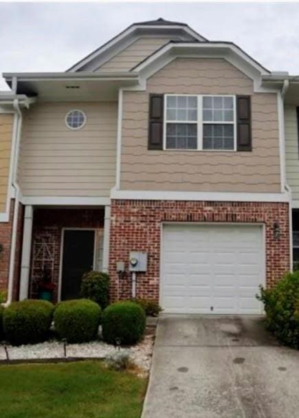 view of front of house with brick siding, an attached garage, and driveway