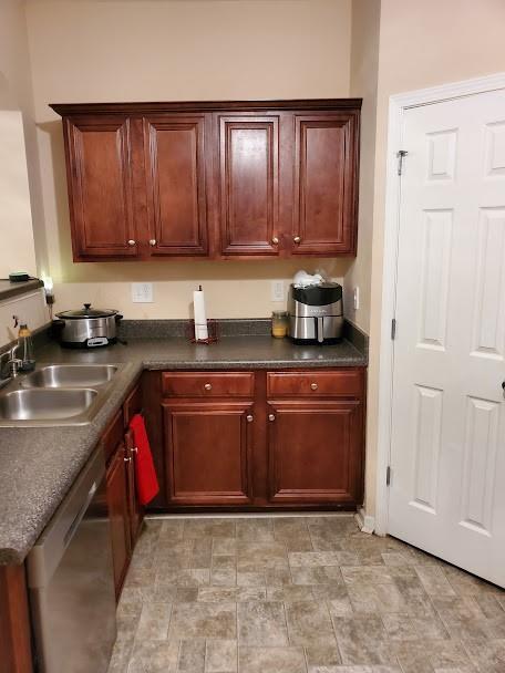 kitchen featuring a sink, dishwasher, and dark countertops