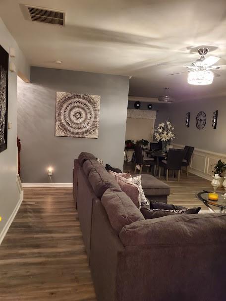 living room with visible vents, ceiling fan, and wood finished floors