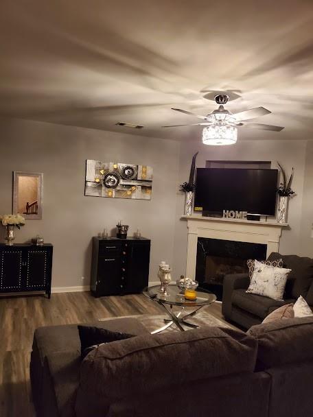 living room with visible vents, wood finished floors, a fireplace, baseboards, and ceiling fan